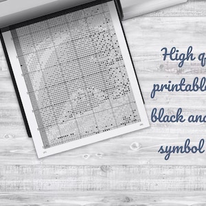 May include: A printed black and white cross-stitch pattern chart. The text on the chart reads "High quality printable PDF black and white symbol chart". The image is on a light wood grain surface.