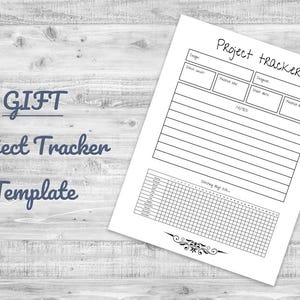 May include: A white Project Tracker Template on a light wood grain surface. The template includes sections for project details, notes, and a habit tracker. The words "GIFT Project Tracker Template" are written in a script font.