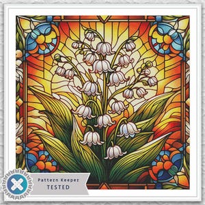 Può includere: Un design di vetrata incorniciato con fiori bianchi di mughetto con foglie verdi. Lo sfondo ha una calda tavolozza di colori arancione, giallo e rosso. Il design è incorniciato in un bordo bianco.