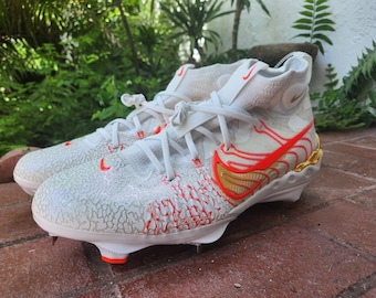 May include: White and red athletic shoes with a gold swoosh logo. The shoes have a textured upper and a white sole with red accents.