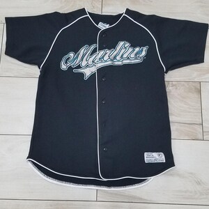 Puede incluir: Jersey de béisbol negro con ribetes blancos y la palabra "Marlins" en una fuente estilizada.