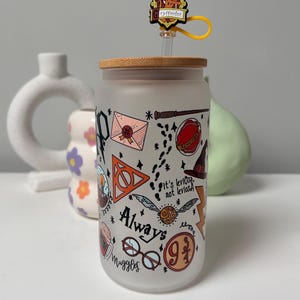 May include: A frosted glass tumbler with a bamboo lid and a straw. The tumbler features a Harry Potter themed design with illustrations of the Hogwarts crest, the Deathly Hallows symbol, a golden snitch, and the words "Always" and "It's LeviOsa, not LevioSA".