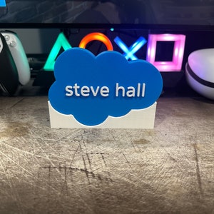 May include: A blue cloud-shaped desk nameplate with the text "steve hall" in white lettering.