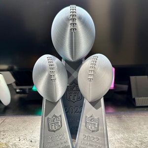 Op de afbeelding: Drie zilveren 3D-geprinte voetbaltrofee&euml;n met de tekst "FFL 2022" en "CHAMPION" op de basis. De bovenste trofee heeft de tekst "Arabian Knights" en de onderste trofee heeft de tekst "Arabian Knights".