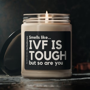 Puede incluir: Una vela beige con una etiqueta negra que dice "Huele como... FIV ES DURO pero tú también".
