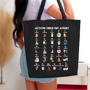 May include: A black tote bag featuring a white graphic of a lactation consultant alphabet. The alphabet is illustrated with icons representing various aspects of lactation consulting, such as attachment, breastfeeding, formula, kangaroo care, latching, and more.