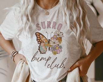May include: A grey t-shirt with a butterfly graphic and the text "Surro bump club."
