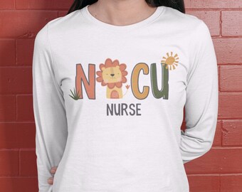Può includere: Maglietta bianca a maniche lunghe con una grafica di un leone e il testo "NCU NURSE".