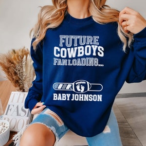 Puede incluir: Sudadera azul marino con el texto "Future Cowboys Fan Loading..." y una barra de progreso con el texto "Baby Johnson".