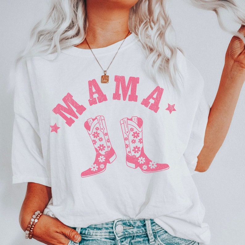 May include: White t-shirt with pink text that says "MAMA" and a pair of pink cowboy boots with floral designs.