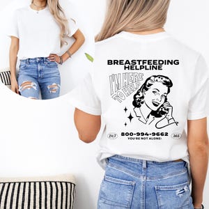 May include: White t-shirt with a black and white illustration of a woman on the phone. The text "Breastfeeding Helpline I'm Here To Help 800-994-9662 You're Not Alone!" is printed on the shirt.