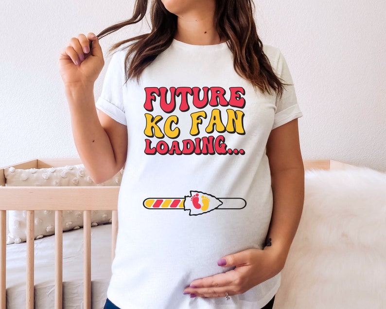 May include: White t-shirt with the text "FUTURE KC FAN LOADING..." in red and yellow letters. A progress bar with a red and yellow arrowhead and two footprints is below the text.