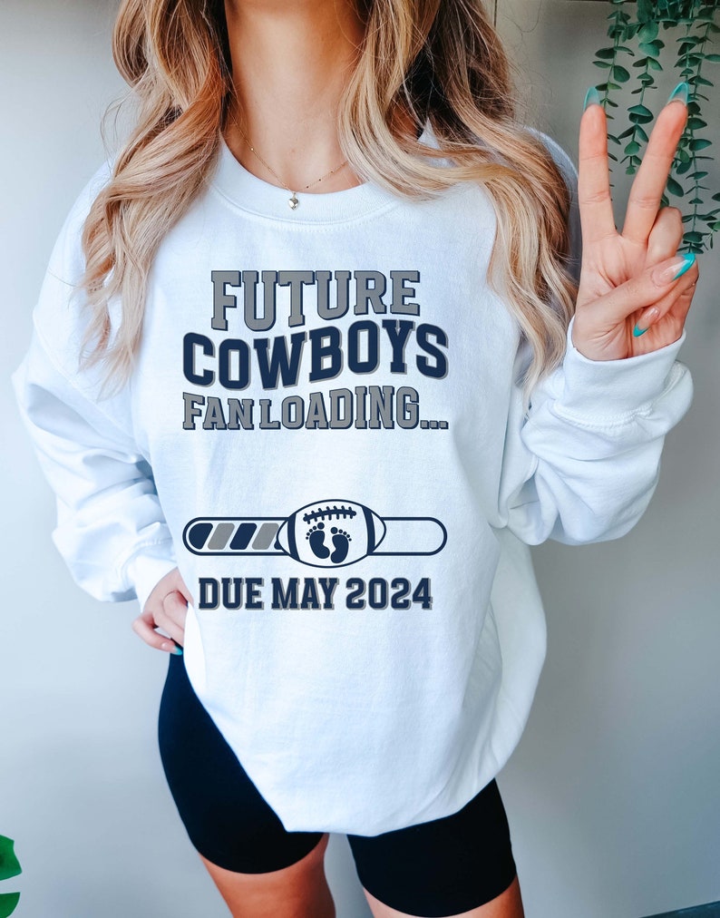 Puede incluir: Sudadera blanca con el texto "Future Cowboys Fan Loading..." y una barra de progreso con un bal&oacute;n de f&uacute;tbol y huellas de pies de beb&eacute;. La barra de progreso indica "Due May 2024".