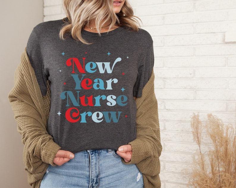 May include: A dark grey t-shirt with the text "New Year Nurse Crew" in blue and red lettering with white stars.