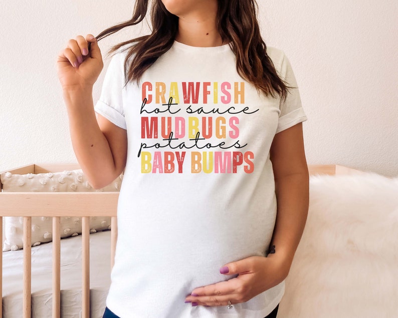 Puede incluir: Camiseta blanca con un gr&aacute;fico colorido que dice "Crawfish hot sauce Mudbugs potatoes Baby bumps".
