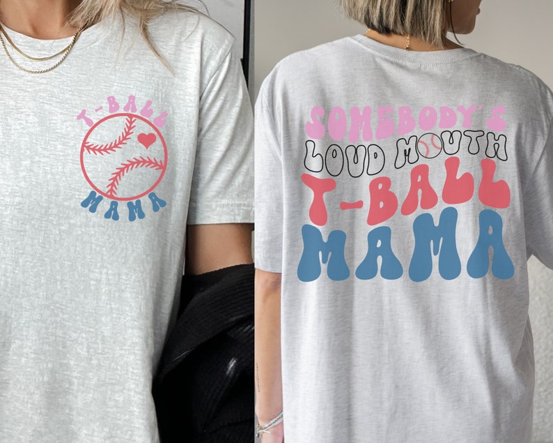 May include: Gray t-shirt with a pink and blue baseball graphic and the text "T-Ball Mama" on the front. The back of the shirt has the text "Somebody's Loud Mouth T-Ball Mama" in pink, red, and blue.