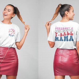 May include: White t-shirt with a red, white, and blue baseball graphic and the text "T-Ball Mama" on the front. The back of the shirt has the text "Somebody's Loud Mouth T-Ball Mama" in a retro font.