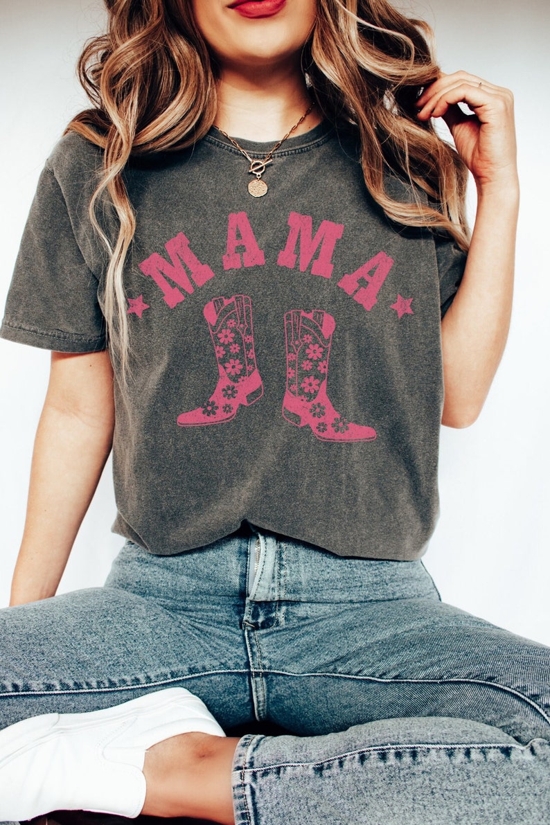 May include: A gray t-shirt with a pink graphic of the word "MAMA" with two pink cowboy boots with floral designs on them.