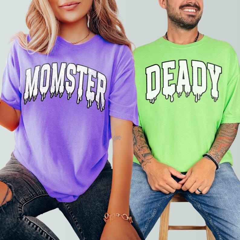May include: Two people wearing matching Halloween shirts. The person on the left is wearing a purple shirt with the text "MOMSTER" in white dripping letters. The person on the right is wearing a green shirt with the text "DEADLY" in white dripping letters.