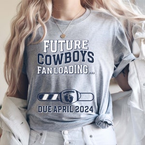 Puede incluir: Una camiseta gris con el texto "FUTURE COWBOYS FAN LOADING..." y una barra de progreso con un bal&oacute;n de f&uacute;tbol y huellas de pies. El texto "DUE APRIL 2024" est&aacute; debajo de la barra de progreso.