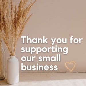 May include: Thank you for supporting our small business. The text is displayed on a light beige wall with two vases of dried pampas grass in front of it. The vases are white and clear glass.