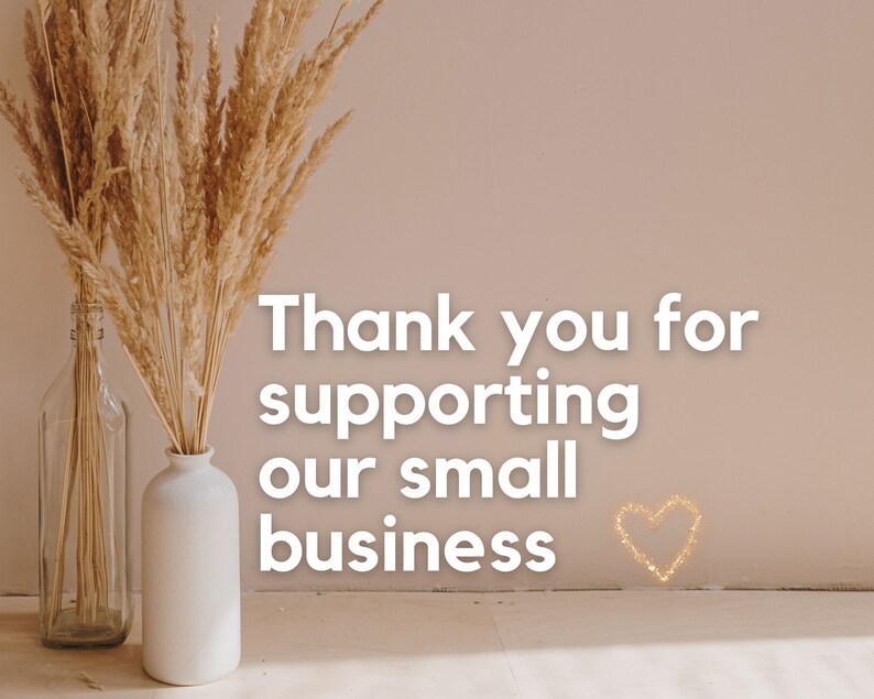 May include: Thank you for supporting our small business. The text is displayed on a light beige wall with two vases of dried pampas grass in front of it. The vases are white and clear glass.