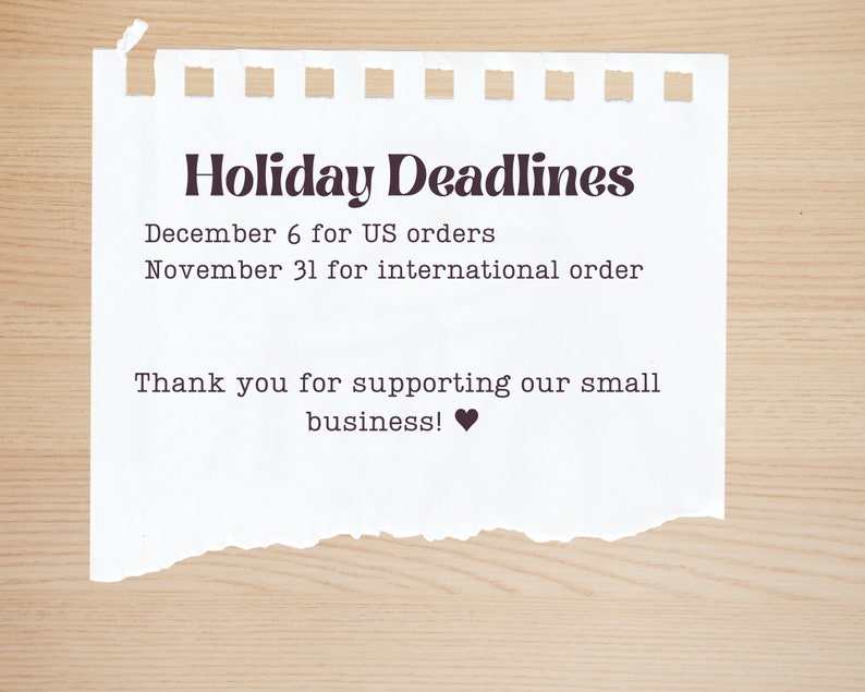 May include: A white piece of paper with a torn edge, with the text "Holiday Deadlines" in black. The text below reads "December 6 for US orders" and "November 31 for international order". The text at the bottom reads "Thank you for supporting our small business!" with a black heart symbol.