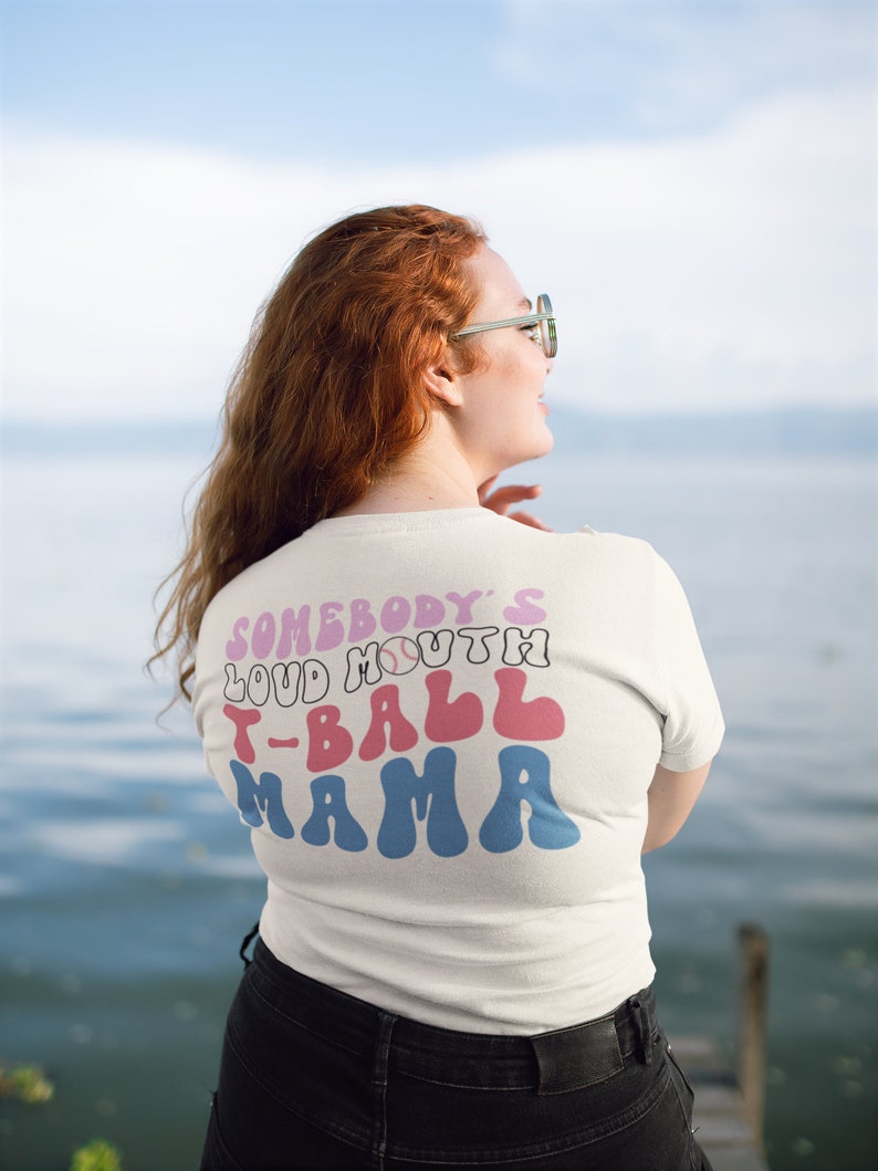 May include: White t-shirt with a pink, blue, and white graphic that says "Somebody's Loud Mouth T-Ball Mama".