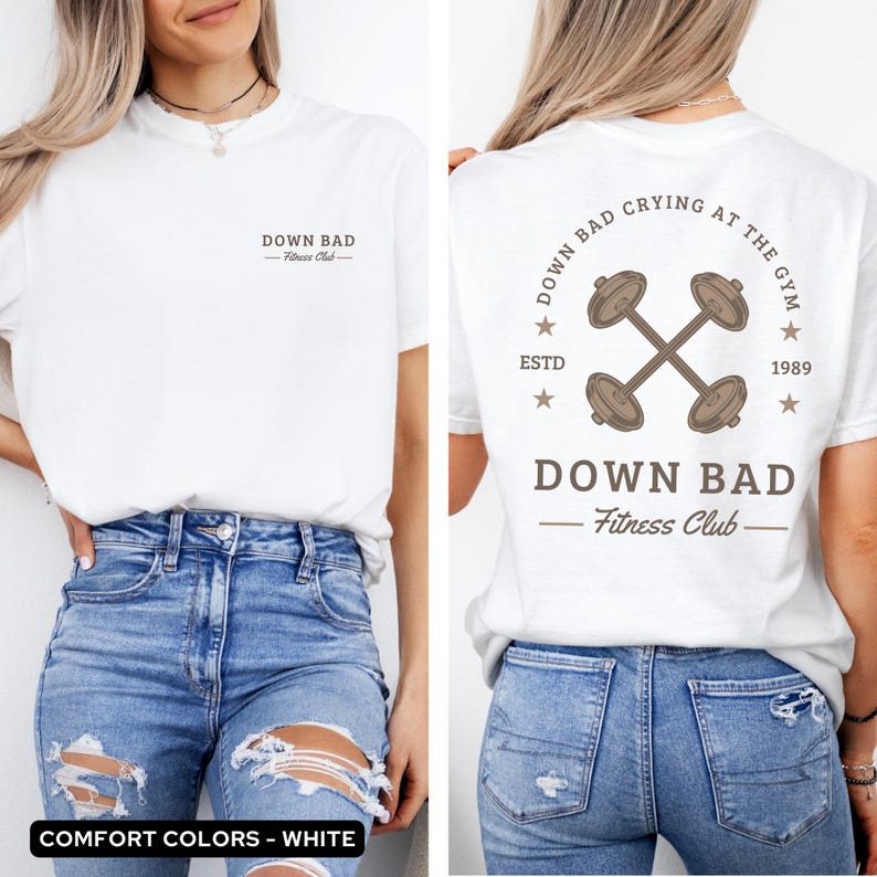 May include: White t-shirt with a graphic of dumbbells and the text "Down Bad Fitness Club" on the back. The front of the shirt has the text "Down Bad Fitness Club" printed on it.