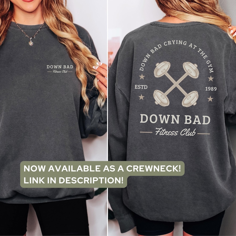May include: A gray sweatshirt with a white graphic on the front that says "DOWN BAD Fitness Club". The back of the sweatshirt has a white graphic of two dumbbells crossed with the text "DOWN BAD CRYING AT THE GYM ESTD 1989".