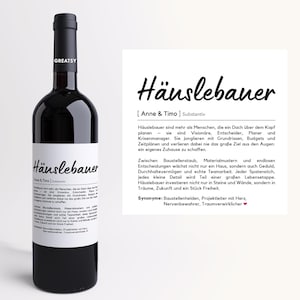 Könnte beinhalten: Eine Flasche Rotwein mit schwarzem Verschluss und weißem Etikett. Das Etikett zeigt das Wort "Häuslebauer" in einer dekorativen Schriftart, zusammen mit anderem Text. Die Flasche ist mit "Greatsy" beschriftet.