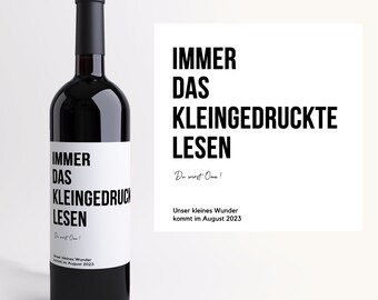 May include: A dark glass wine bottle with a black cap and a white label. The label features the German text "IMMER DAS KLEINGEDRUCKTE LESEN" in bold black letters. A separate white card displays the same text and "Du wirst Oma!" and "Unser kleines Wunder kommt im August 2023".