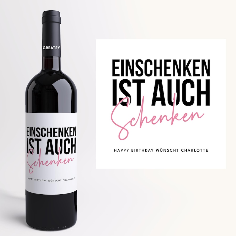 May include: A dark red wine bottle with a white label featuring the text "EINSCHENKEN IST AUCH Schenken" in black and pink. The label also includes "HAPPY BIRTHDAY W&Uuml;NSCHT CHARLOTTE". The bottle has a black cap.