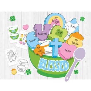 May include: A green bowl filled with colourful shapes, each with a word written on it, such as "God", "family", "friends", and "my dog". The bowl is labelled "BLESSED" and there is a spoon next to it.