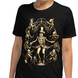 Puede incluir: Camiseta negra con un gráfico dorado de un hombre con un sombrero de copa rodeado de figuras. El hombre sostiene un palo y las figuras están en varias poses.