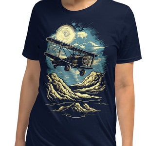 May include: A navy blue t-shirt with a graphic of a vintage airplane flying through the clouds under a full moon. The graphic is in shades of yellow, brown, and white.