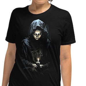 May include: A black t-shirt with a graphic print of a woman in a hooded cloak holding a lit candle. The woman's face is visible and she has a serious expression.