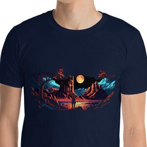 May include: A navy blue t-shirt with a pixelated graphic of a landscape with a red moon, a castle, and a lone figure standing in the foreground.
