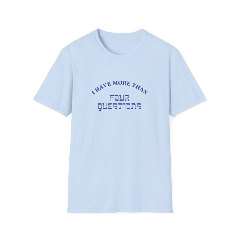 May include: Light blue t-shirt with a crew neck and short sleeves. The shirt features the text "I HAVE MORE THAN FOUR QUESTIONS" in navy blue, arched above the word "QUESTIONS" in a stylized font.