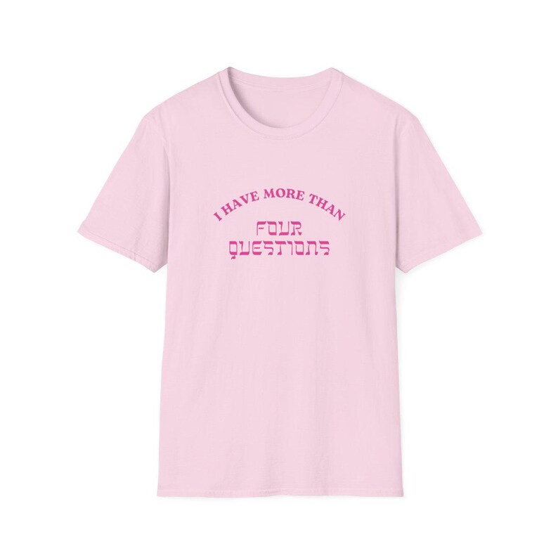 May include: A light pink t-shirt with the text "I HAVE MORE THAN FOUR QUESTIONS" in a darker pink, arched above and below the words. The shirt has short sleeves and a crew neck.
