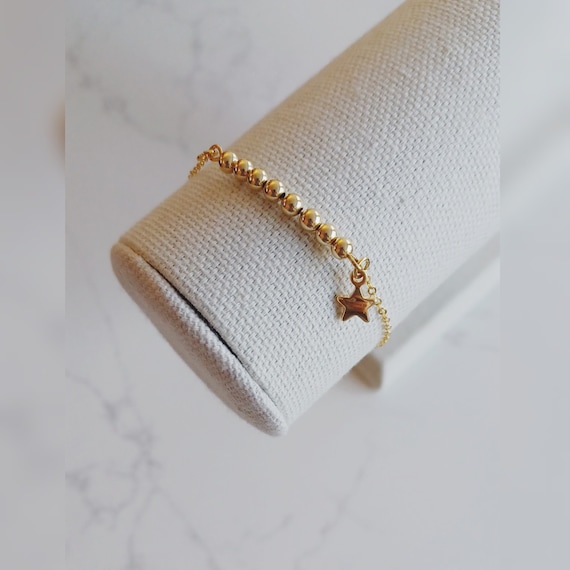Gold beaded bracelet with charm best sale