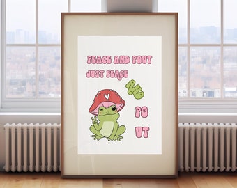 May include: A framed print with a white background featuring a green frog wearing a pink mushroom hat. The text "Peace and Pout Just Peace" is written in pink letters above the frog. The frog is holding up two fingers in a peace sign.