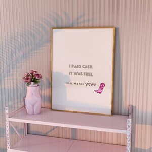 Może przedstawiać: Wydruk w ramie ze złotą ramką i białym tłem. Wydruk zawiera tekst "I paid cash. It was free. Girl Maths X♡X♡". Wydruk znajduje się na różowej półce.