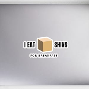 Puede incluir: Un portátil blanco con una pegatina que dice "Me como las espinillas para el desayuno". La pegatina presenta una caja marrón con un contorno blanco.