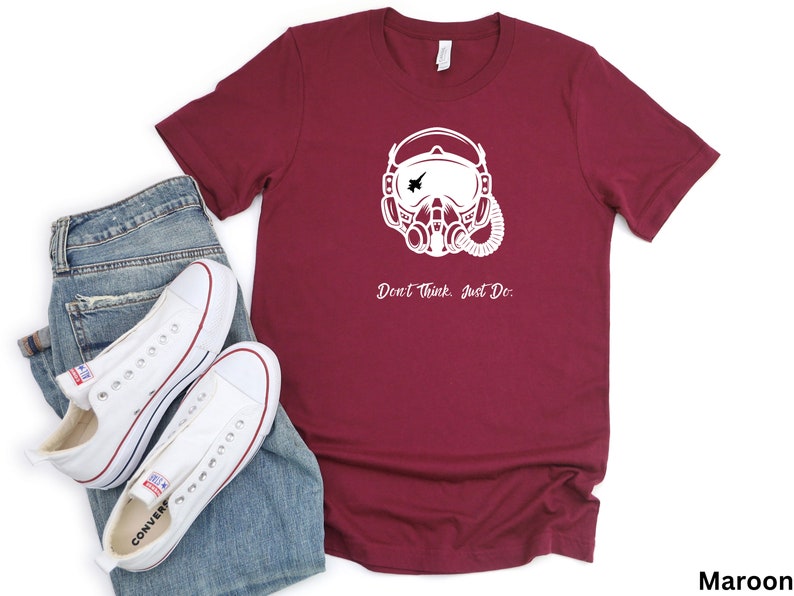 May include: A maroon t-shirt with a white graphic of a pilot wearing a helmet and oxygen mask. The text "Don't think. Just Do." is printed below the graphic.