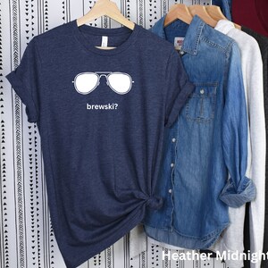 Puede incluir: Una camiseta azul marino jaspeada con un gr&aacute;fico blanco de gafas de sol y el texto "brewskis?"