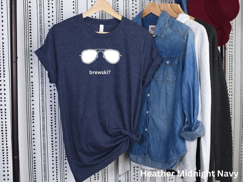 Puede incluir: Una camiseta azul marino jaspeada con un gr&aacute;fico blanco de gafas de sol y el texto "brewskis?"
