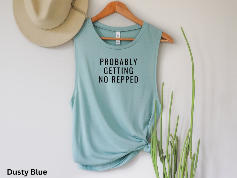 Op de afbeelding: Stofkleurig blauw tanktop zonder mouwen met de tekst "Probably Getting No Repped" in zwart gedrukt.