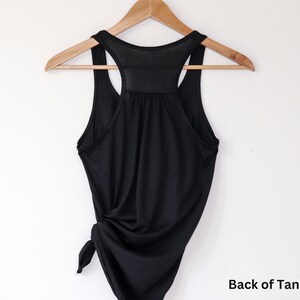 May include: Black tank top with a racerback style. The back of the tank top is tied in a knot at the bottom.