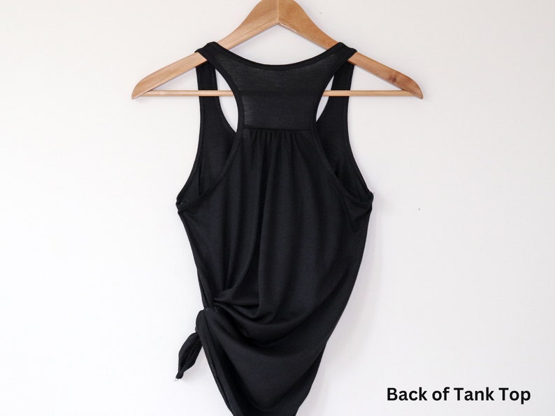 May include: Black tank top with a racerback style. The back of the tank top is tied in a knot at the bottom.